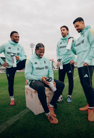 Stanley 1913 water bottles held by four Juventus players in mint training gear on a grass pitch.